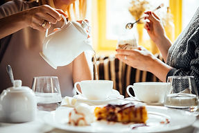 picture of two people sharing a cup of tea and desserts