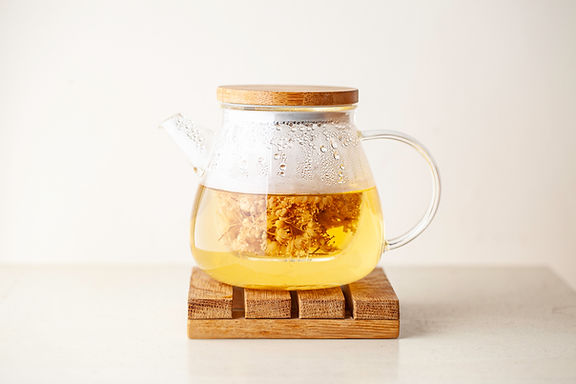 Clear teapot with flower blooming tea on a wood block